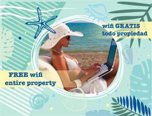 a woman sitting on a beach with a laptop at DUKASI ESCAPE playa LOS CORALES in Punta Cana