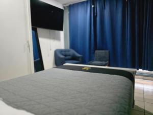 a bedroom with a bed and a chair and blue curtains at 10 VENATOR House Boutique in León