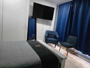 a bedroom with a bed and a chair and a flat screen tv at 10 VENATOR House Boutique in León +12 photos