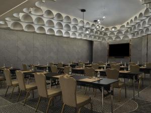 a dining room with tables and chairs and a screen at SO/ Uptown Dubai in Dubai