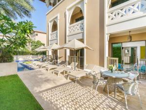 a group of chairs and tables and umbrellas next to a building at Rixos Premium Saadiyat Island - All Inclusive in Abu Dhabi