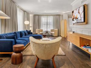 a living room with a blue couch and a chair at Ändra Hotel Seattle - MGallery Collection in Seattle