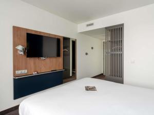 a hotel room with a bed and a flat screen tv at Ibis Rouen Centre Rive Gauche Mermoz in Rouen +88 photos