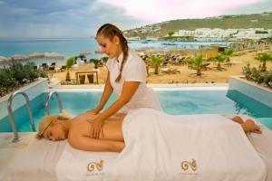 a woman laying on a massage bed next to a pool at Thalassa boutique hotel-Adults only in Platis Gialos