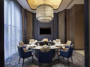 a dining room with a table and blue chairs at Sofitel Xiong An in Baoding