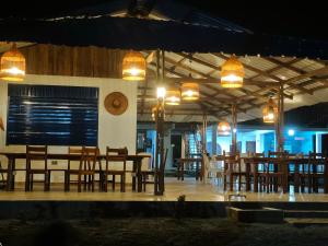 a restaurant with wooden tables and chairs and lights at Cabañas Iracas del Mar in Nuquí