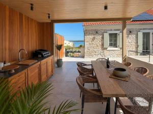 an outdoor kitchen with a wooden table and chairs at Heritage Villa Francheza-Elegant Stone villa near the Beach, Pašman Island , Ugrinić in Ugrinići