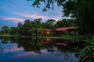 a resort with a reflection in the water at dusk at Maquenque Lodge in Boca Tapada