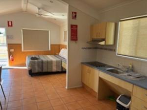 a bathroom with a sink and a bed in a room at Longreach Starlight Cabins - Boutique Outback Accommodation in Longreach