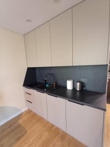 a kitchen with white cabinets and a black counter top at Labaresto Plaza jums in Vilnius