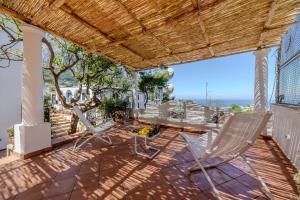 a patio with chairs and a table on a roof at Villa Preziosa - Panoramic Sea View in Capri