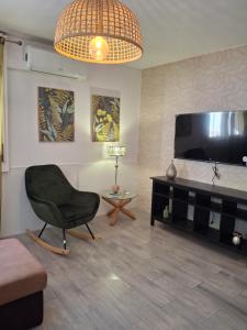 a living room with a chair and a flat screen tv at Casa da Avenida in Mértola