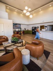 a person walking through a lobby with leather chairs and tables at Kokopelli Inn Sedona, Trademark Collection by Wyndham in Sedona +93 photos