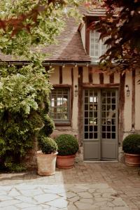 a house with a door and some plants in pots at La Dime de Giverny - Chambres d'hôtes-Spa-Restaurant in Giverny