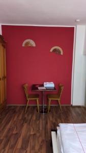 a room with a table and two chairs against a red wall at Campus Hotel - ehemals Hotel Paseo in Aachen +31 photos