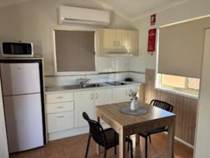 a kitchen with a table and chairs and a refrigerator at Longreach Starlight Cabins - Boutique Outback Accommodation in Longreach +26 photos
