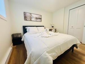 a bedroom with a large bed with white sheets at Your Cozy NL Haven in St. John's