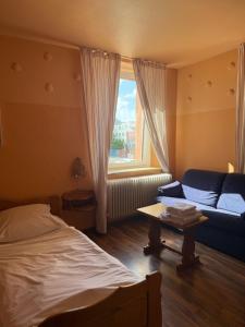 a bedroom with a bed and a couch and a window at Campus Hotel - ehemals Hotel Paseo in Aachen