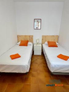 two beds in a small room with orange pillows at APARTBEACH BALANDRO VISTAS MAR in Cambrils