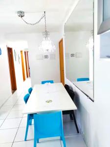 a dining room with a white table and blue chairs at Lindo apartamento em Muro Alto, Porto de Galinhas, Vista para as piscinas, 3 qtos e sala climatizados, Acomoda até 8 pessoas in Ipojuca +85 photos