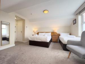 a bedroom with two beds and a chair and a window at Somerton House Rooms Only in Belfast