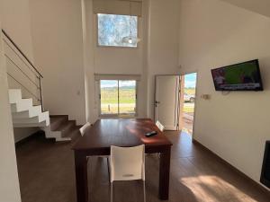 a dining room with a wooden table and white chairs at Cabañas Aires del Bosque in Santa Teresita