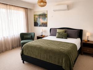 a bedroom with a bed and a green chair at Muswellbrook Motor Inn in Muswellbrook +42 photos