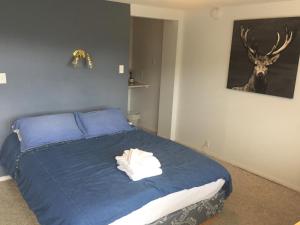 a bedroom with a bed with blue sheets and a deer picture at Misty River Lodge - in Radium Hot Springs +26 photos