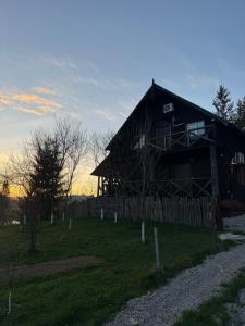 a large wooden cabin in a field with a fence at Вершина in Vorokhta