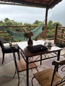 a table and chairs on a patio with a hammock at Casa Águas Claras in Palmeiras