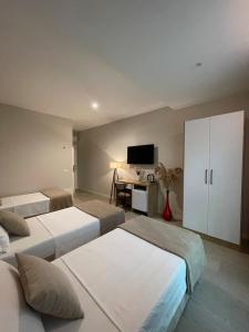 a bedroom with three beds and a desk with a tv at Solea Hotel in Vlorë