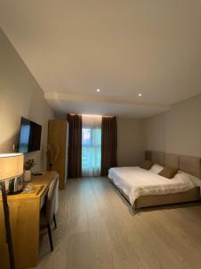 a bedroom with a bed and a desk and a television at Solea Hotel in Vlorë
