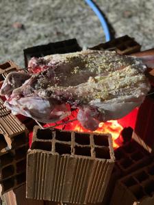 a piece of meat is cooking on a grill at Pousada degamix in Barroquinha