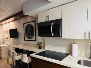 a kitchen with white cabinets and a black microwave at Renovated Beachfront Condo with Balcony in Sunny Isles Beach