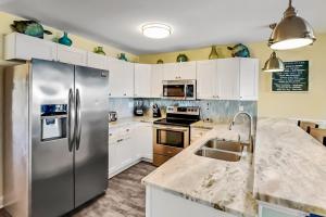a kitchen with a stainless steel refrigerator and white cabinets at Put-in-Bay Waterfront Condo #207 in Put-in-Bay