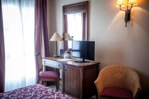 a hotel room with a desk with a television and a bed at Gran Hotel Ciudad Del Sur in Puerto Real