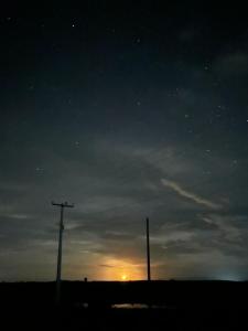 a sunset with two telephone poles in a field at Pousada degamix in Barroquinha
