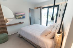 a bedroom with a white bed and a window at Avli Residences in Kos