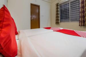 a bed with red and white sheets and a window at Hotel O Sagar Comforts in Bangalore