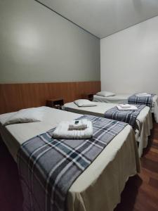 a room with three beds with towels on them at Hotel Elithi - O melhor custo benefício in Itapeva