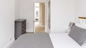 a white bedroom with a bed and a hallway at Govandale Seaviews in Kingarth