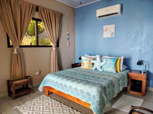 a bedroom with a bed with a blue wall at Mar y Sombra Villas in Quepos
