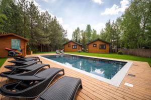 a swimming pool with chairs on a wooden deck at Osada nad Wdą w Borsku in Borsk