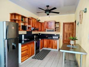 a kitchen with wooden cabinets and a black refrigerator at Mar y Sombra Villas in Quepos