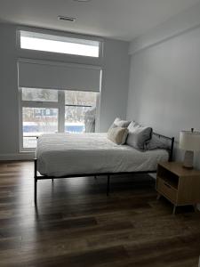 a white bedroom with a bed and a window at New The Carlyle 209 Beachside Condo in Grand Bend in Grand Bend