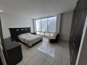 a bedroom with a bed and a chair and a window at Modern apartment Altravia 6 tower in Cholula