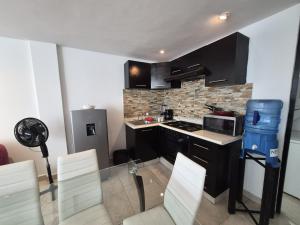 a small kitchen with black cabinets and white chairs at Modern apartment Altravia 6 tower in Cholula