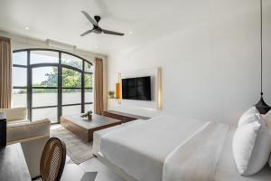 a white bedroom with a bed and a living room at Avida Studios in Uluwatu - 5 mins walk to Thomas Beach in Uluwatu