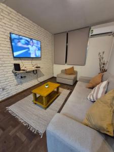 a living room with a couch and a tv on a brick wall at Apartamento IdeaL Independencia VI in Mendoza