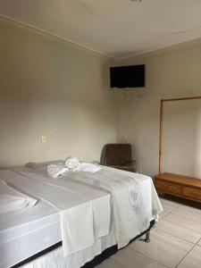a bedroom with a white bed and a television at Hospedagem Riazo in Pirenópolis +2 photos